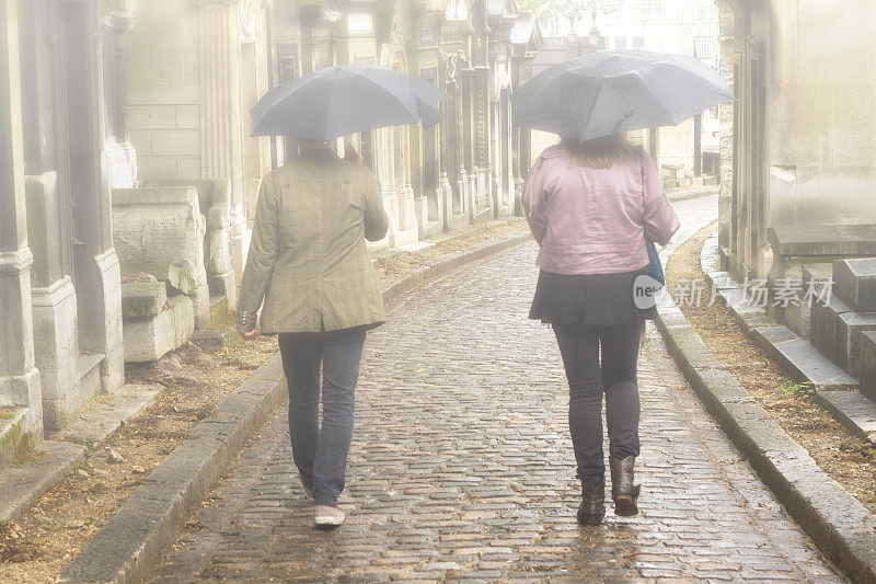 法国巴黎:一对情侣在雨中漫步，地点:Père Lachaise